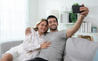 © Basicdog - Cheerful Caucasian man hugging his woman and looking at mobile phone screen.