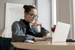 © muse studio - The manager with glasses works online on the Internet, workplace. A woman uses a computer on a table. Prints text on the laptop keyboard.