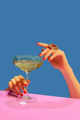 Female hands holding glass with champagne over blue pink background. Festive celebration. Food pop art