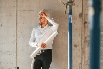 Wall Mural - Manager is in the formal clothes. Holding plan in hands. Man is working on the construction site at daytime