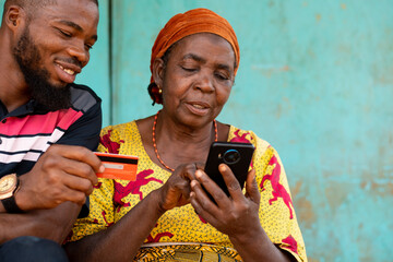 elderly woman and young man using phone and credit card