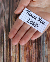 Wall Mural - Hand holding a note with handwritten text: Thank You LORD over wooden table. Vertical shot, a closeup. Thanksgiving and gratitude message, Christian biblical concept. Top view.