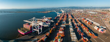 The Oakland Outer Harbor Aerial View. Loaded Trucks Moving By Container Cranes. View Of Busy Port Of Oakland. Shipping Terminal Facility.