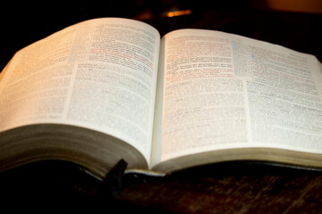 Wall Mural - holy bible open on a wooden table with its sides slightly heavy