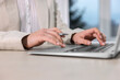 © New Africa - Woman with pen working on laptop at wooden table, closeup. Electronic document management