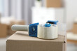 Dispenser with roll of adhesive tape on box indoors, closeup