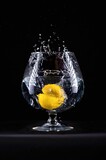 Fototapeta Łazienka - lemon splashing into water in wine glass on black background 