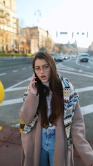 Wall Mural - A young woman is talking on the phone on a city street