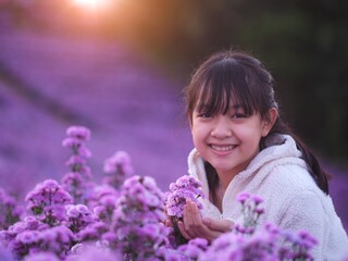 Wall Mural - A brightly smiling little girl in white coat stands in a field of margarets flowers