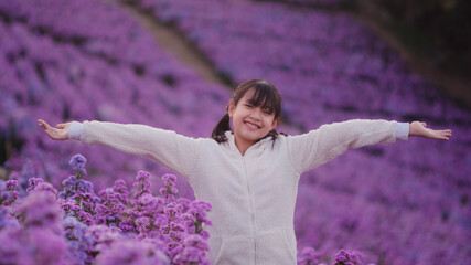 Wall Mural - Freedom asian little girl in white coat stands in a field of margarets flowers