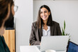 © Westend61 - Happy businesswoman with laptop looking at colleague in office