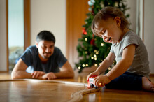 Happy Son And Father Playing With Toy Train At Home