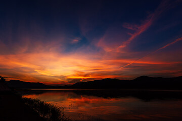 Wall Mural - sunrise time at lake or river with mountain on the background. in dark tone.