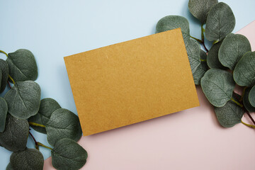 Poster - Empty invitation card mockup with green eucalyptus leaves on pink and blue background