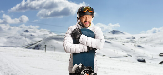 Sticker - Young man hugging a snowboard and posing on a mountain