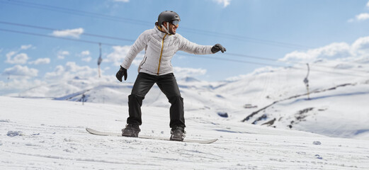 Sticker - Full length shot of a man riding a snowboard on a hill