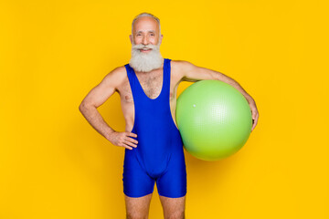 Sticker - Photo of cheerful sporty granddad put hand waist hold fit ball isolated on yellow color background