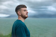 © Евгений Шемякин - Serious pensive thoughtful handsome happy guy, young man enjoying sea, ocean view, landscape, looking into distance at summer day in tropical country at storm with cloudy sky, breathing deep fresh air