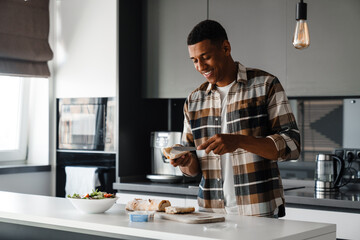 Canvas Print - Young african man cooking in kitchen at home