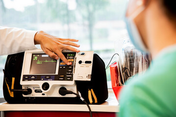 A doctor and nurse look at vitals on a machine in the hospital