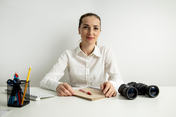 Wall Mural - Young woman in a white shirt with binoculars sitting in the office