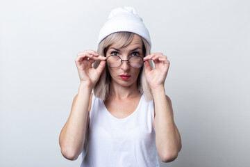 Wall Mural - Pensive young woman looks out from under the glasses on a light background