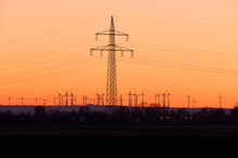 Electricity Pylons And Wind Turbines In Countryside At Sunset; Biebesheim Am Rhein, Hesse, Germany