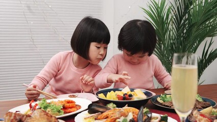 Canvas Print - テーブルに並べられたクリスマスの料理を食べる子供