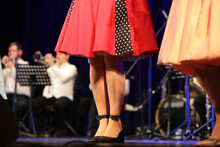 A Woman In A Red Dress On Stage In Front Of An Orchestra Of Musicians