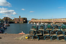 Lobster Traps Piled Along The Shore With Boats Moored In The Small, Tranquil Victoria Harbour At Dunbar, Scotland; Dunbar, East Lothian, Scotland