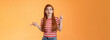 Complicated questioned redhead girlfriend trying understand what happening, which way go, look around, pointing sideways up and right, frowning perplexed, taking hard decision, orange background