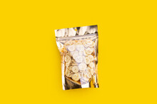 Banana Slice Chips In Package Bag On Yellow Background.