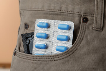 Wall Mural - Pants with pills and condom in pocket, closeup. Potency problem