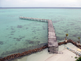 wooden pier on tropical beach with turquoise water