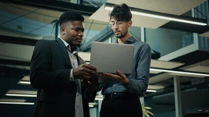 Business partners male businessmen stand in office african man banker agent consulting arabian client with laptop discussing bank loan deal benefits develop online web project two ethnic men negotiate