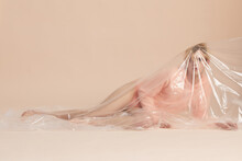 Full Shot Of Sensual Male Model In Pastel Peach Clothing Covered With Plastic Posing On Camera