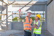 © ND STOCK - Two professionals inspect construction site of commercial building, industrial building, real estate project  civil engineer, investor using laplet in background crane, skyscraper, concrete formwork