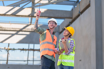 Wall Mural - Two professionals inspect construction site of commercial building, industrial building, real estate project  civil engineer, investor using laplet in background crane, skyscraper, concrete formwork