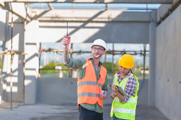 Wall Mural - Two professionals inspect construction site of commercial building, industrial building, real estate project  civil engineer, investor using laplet in background crane, skyscraper, concrete formwork