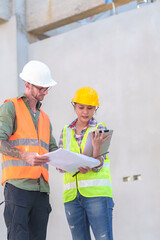 Wall Mural - Two professionals inspect construction site of commercial building, industrial building, real estate project  civil engineer, investor using laplet in background crane, skyscraper, concrete formwork