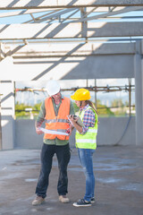 Wall Mural - Two professionals inspect construction site of commercial building, industrial building, real estate project  civil engineer, investor using laplet in background crane, skyscraper, concrete formwork