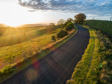 Narrow Country Road In Hills With Golden Sunlight At Sunset