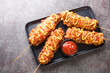 Korean corn dogs are hot dogs, cheese, French fries fried in a batter on a stick and dressed with sugar, ketchup, mustard closeup on the plate on the table. Horizontal top view from above