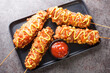 Korean corn dogs or Korean hot dogs are popular local street food, typically made of sausages or mozzarella cheese on sticks deep-fried closeup on the plate. Horizontal top view from above