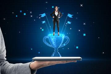 Aufkleber - hand holding tablet with attractive happy young european businesswoman and glowing winner's cup hologram on blurry blue bokeh background.