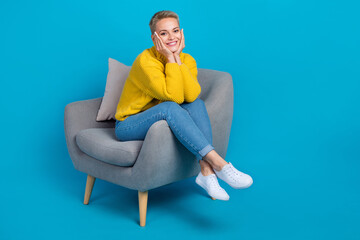 Wall Mural - Full length photo of satisfied dreamy cute blonde short hair woman touch cheeks comfort armchair lovely look you isolated on blue color background