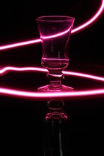 Copa De Brindis Para Champàn De Cristal Transparente En El Bar, Con Luz De Neòn Color Rosa Forma  Un Diseño Abstracto Con Lìnea Y Cìrculo En Fondo Negro, Una Bella Ilustraciòn Para Fondos De Diseño