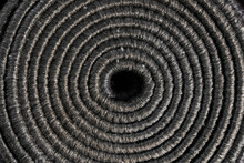 Textured Backdrop Of Tight Rolled Up Grey Carpet Edge, With Void In Middle. Above View Of Twisted, Coiled Natural Grey Jute Pattern As Background. Concept Of Textures And Backgrounds. 