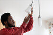 © Connect Images - Young man changing bulb in electric light