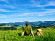 canvas print picture - Bayern, Allgäu, Mann, Person beim Wandern macht Pause, Rast auf Wiese mit Aussicht auf Berge